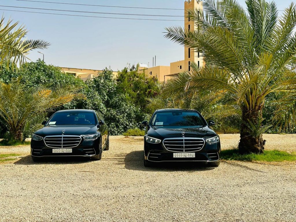 Professional chauffeur standing beside black SUV ready to assist